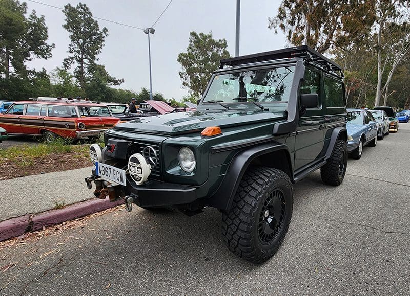 A rugged green off-road vehicle parked outdoors with a winch on the front.