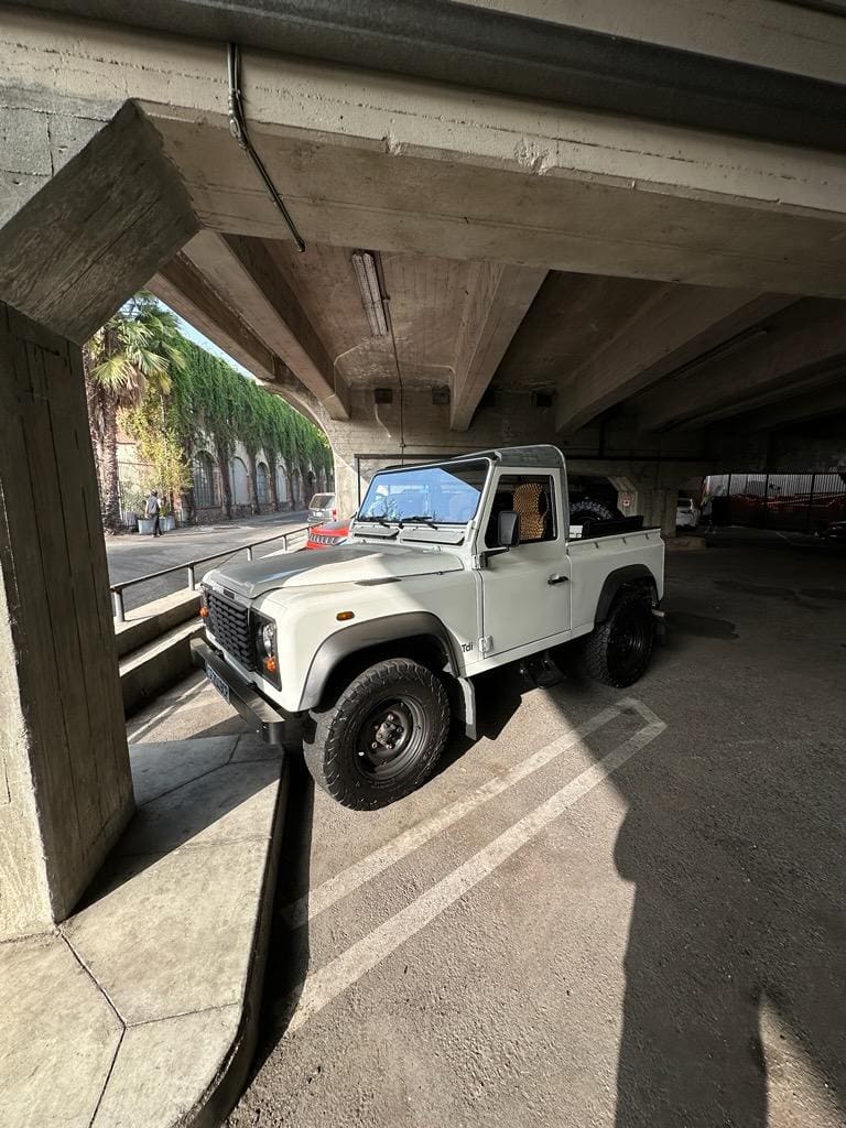 White off-road vehicle parked under a concrete structure.