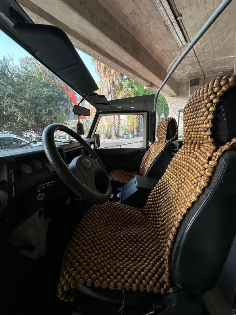 Interior of a car with wooden bead seat covers and a view outside.