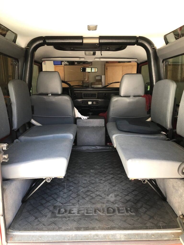 Interior of a vehicle with two rows of side-facing seats and a front driving area.
