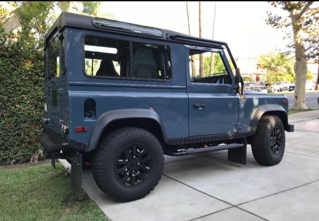 Blue off-road vehicle parked on driveway with tinted windows.