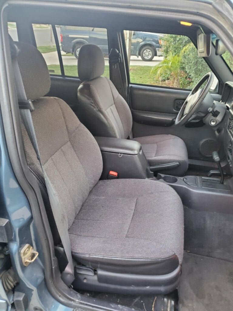 Interior view of a vehicle showing two front seats and the dashboard.