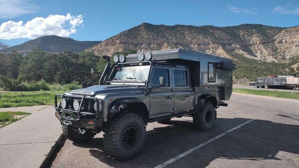 A rugged black off-road vehicle parked by mountainous terrain under a clear sky.