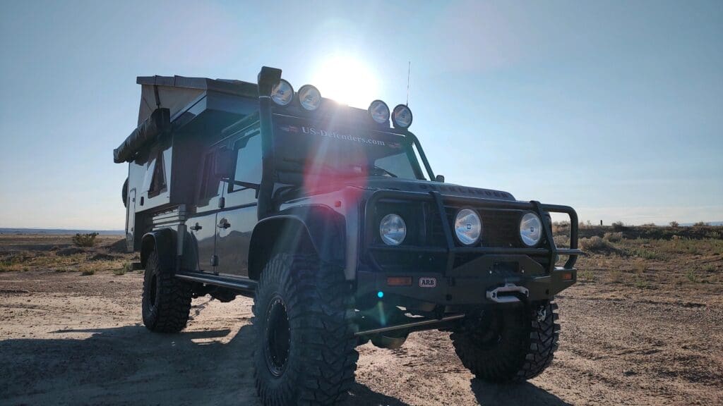 Off-road vehicle parked on rocky terrain under bright sun.