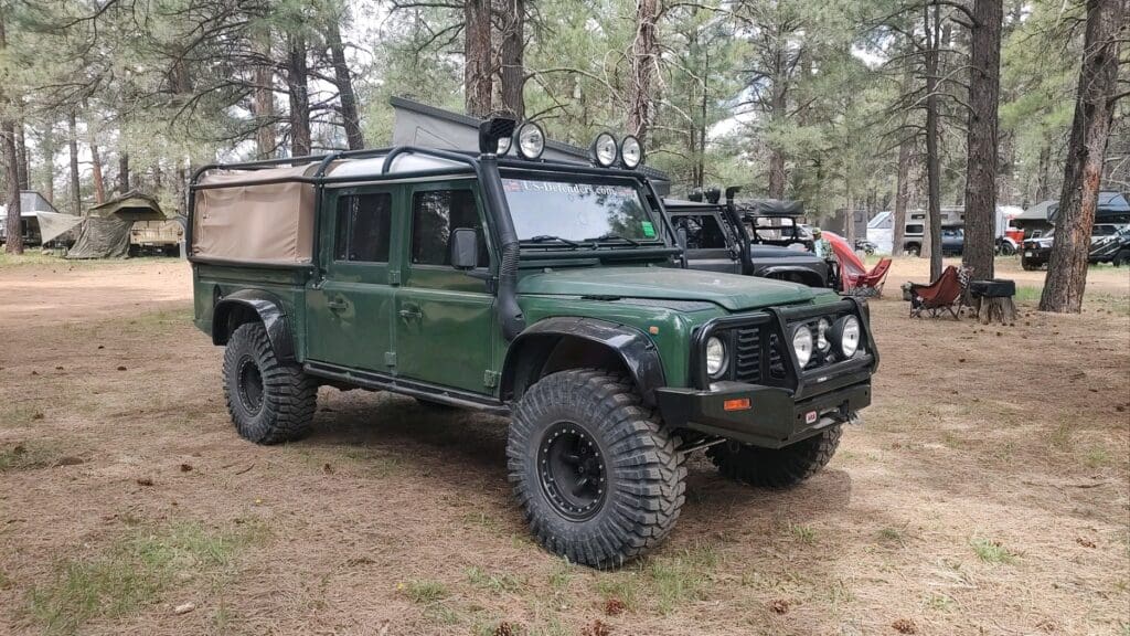Green off-road truck with large tires parked in forest.