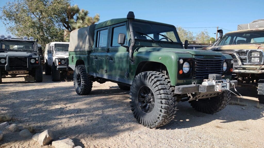 Green off-road vehicle with large tires parked outdoors in sunlight.