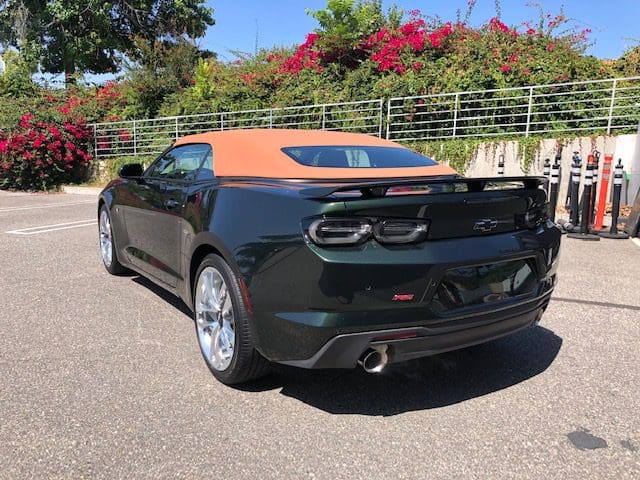 Black sports car with orange roof parked outdoors under clear sky.