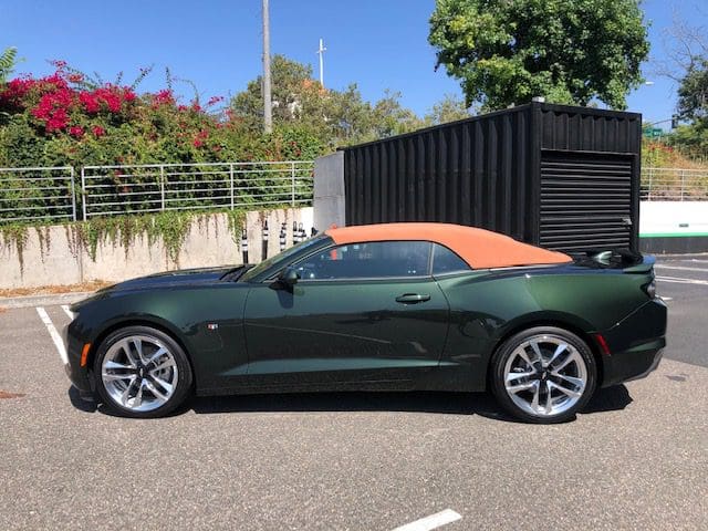 Green convertible car with orange soft top parked outdoors.