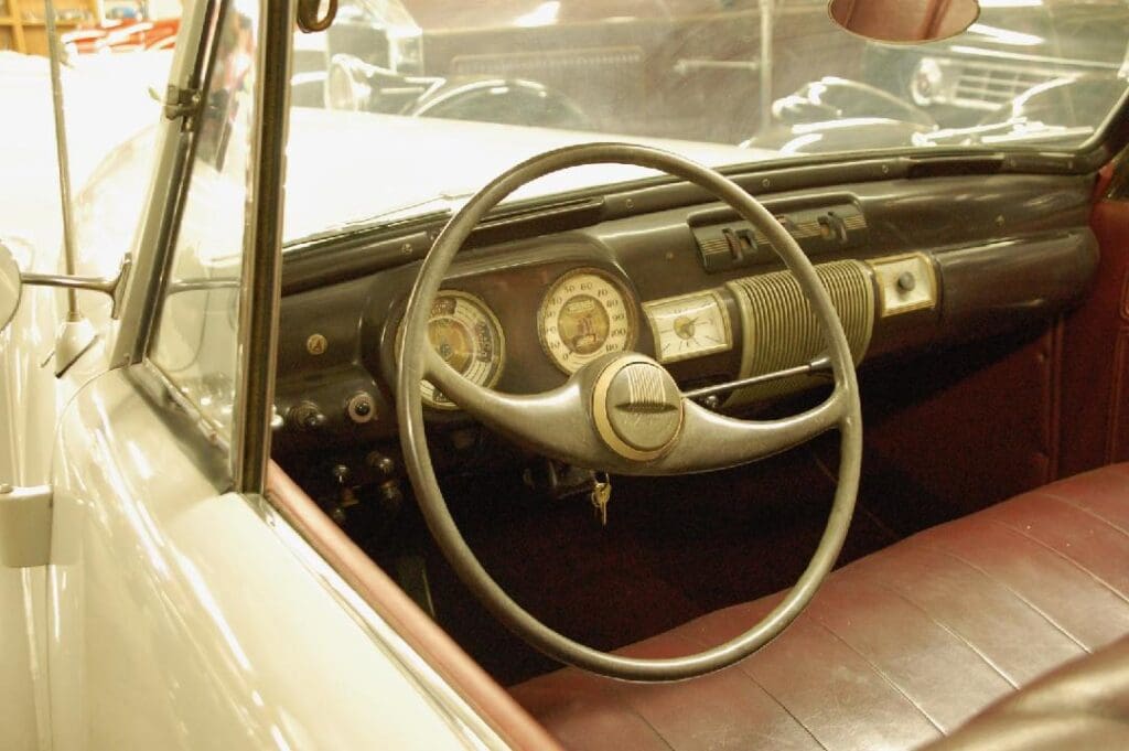 Vintage car interior with a classic steering wheel and dashboard.