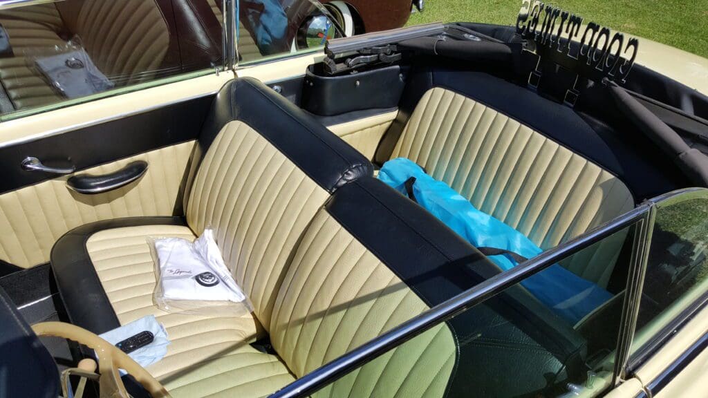 Vintage convertible car interior with cream and black seats.