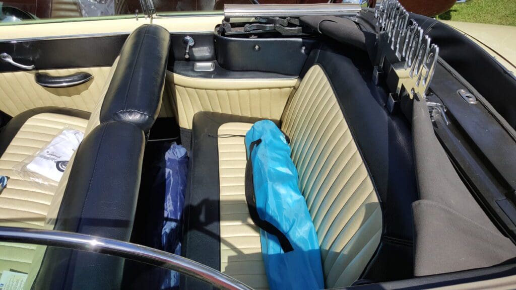 Interior of a vintage car with striped seats and a blue umbrella.