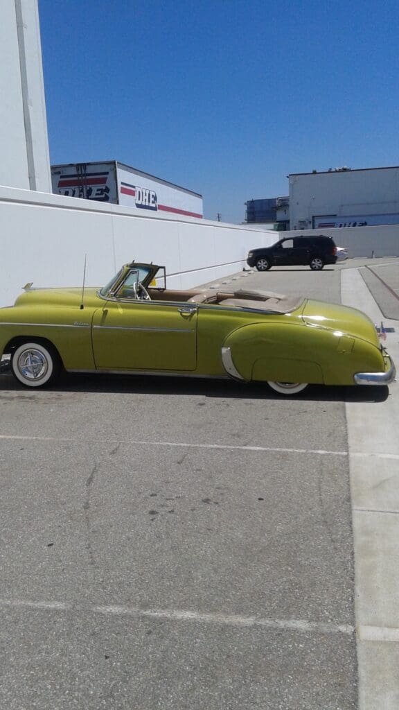 Classic yellow convertible car parked in a sunny lot.