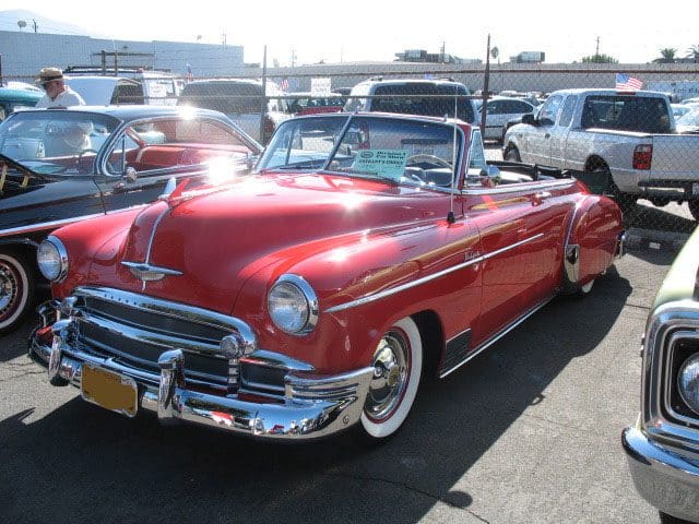 A shiny red classic convertible car parked in a lot.