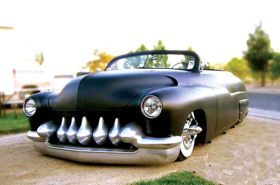 Classic black custom car with shiny chrome teeth grille and sleek design.