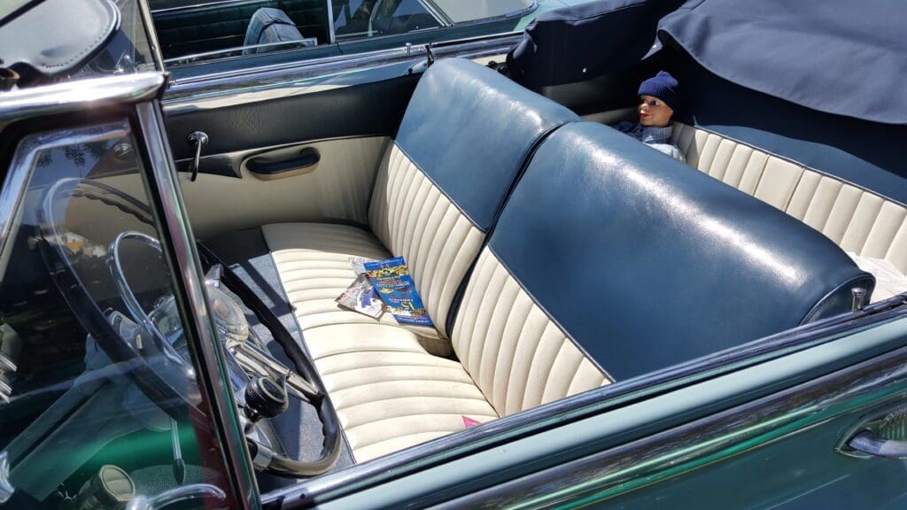 Vintage car interior with blue and white leather seats and keys on the seat.