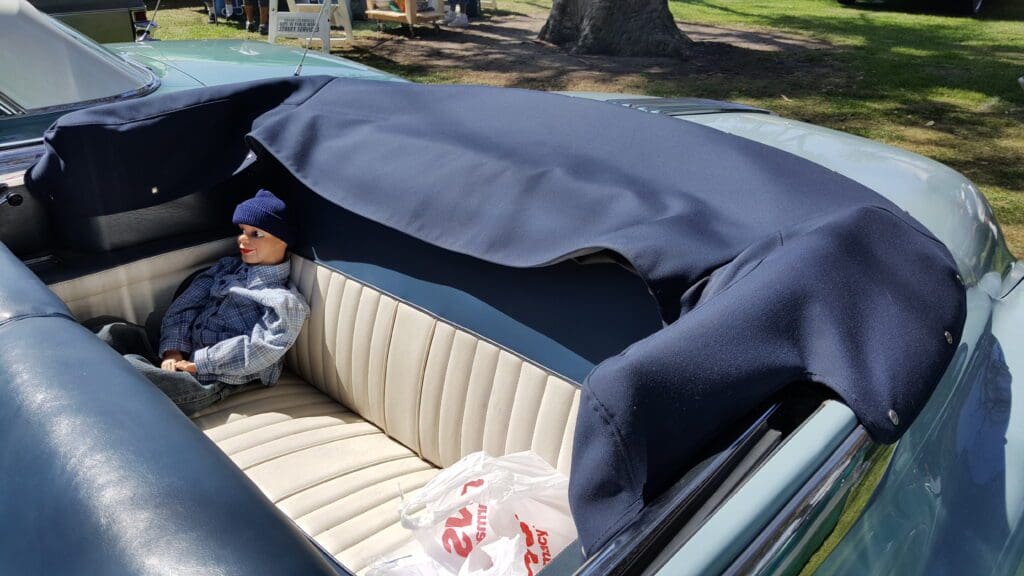 Classic convertible car with navy blue soft top and cream leather seats.