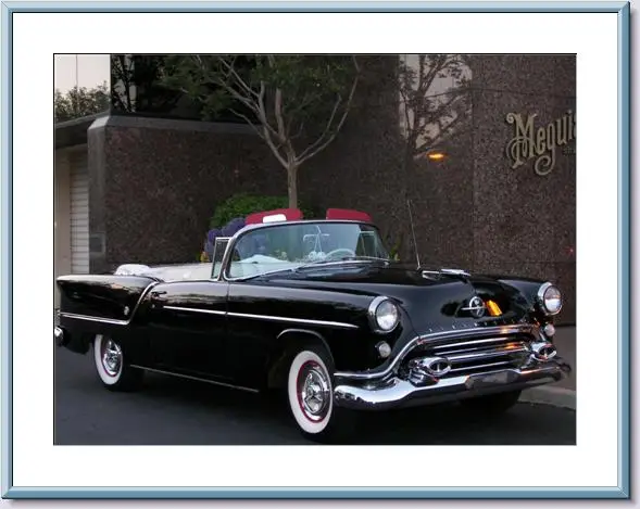 Classic black convertible car parked on the street at dusk.