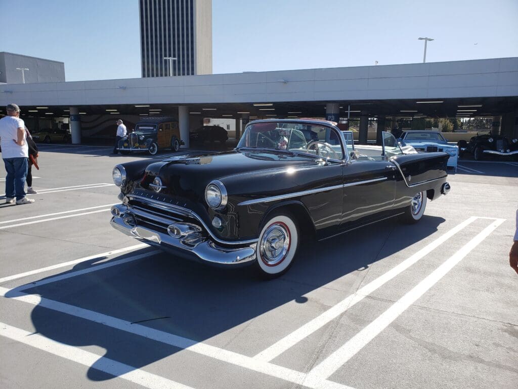 Classic black convertible car parked in a sunny lot.
