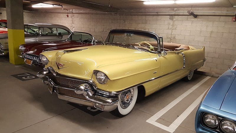 Classic yellow convertible parked in an indoor garage.