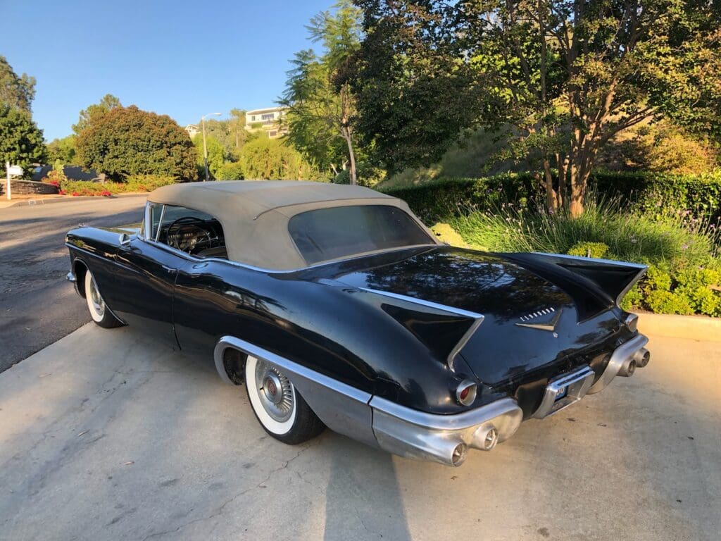 Classic black convertible car parked outdoors with whitewall tires.