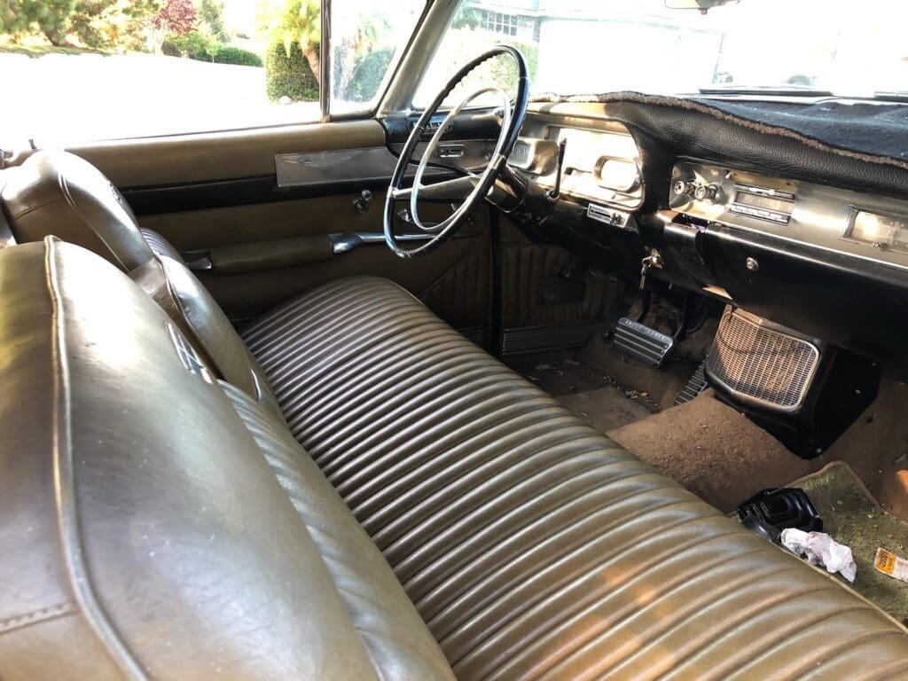 Vintage car interior with large bench seat and classic dashboard.