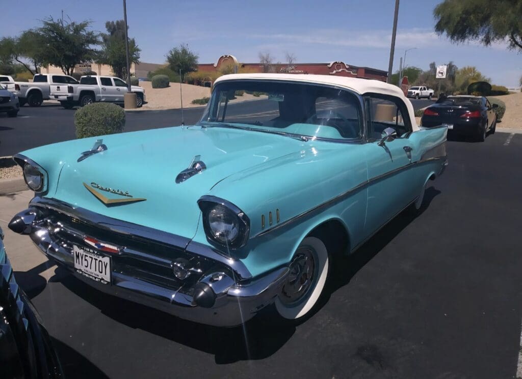 Classic turquoise and white vintage car parked under a clear blue sky.