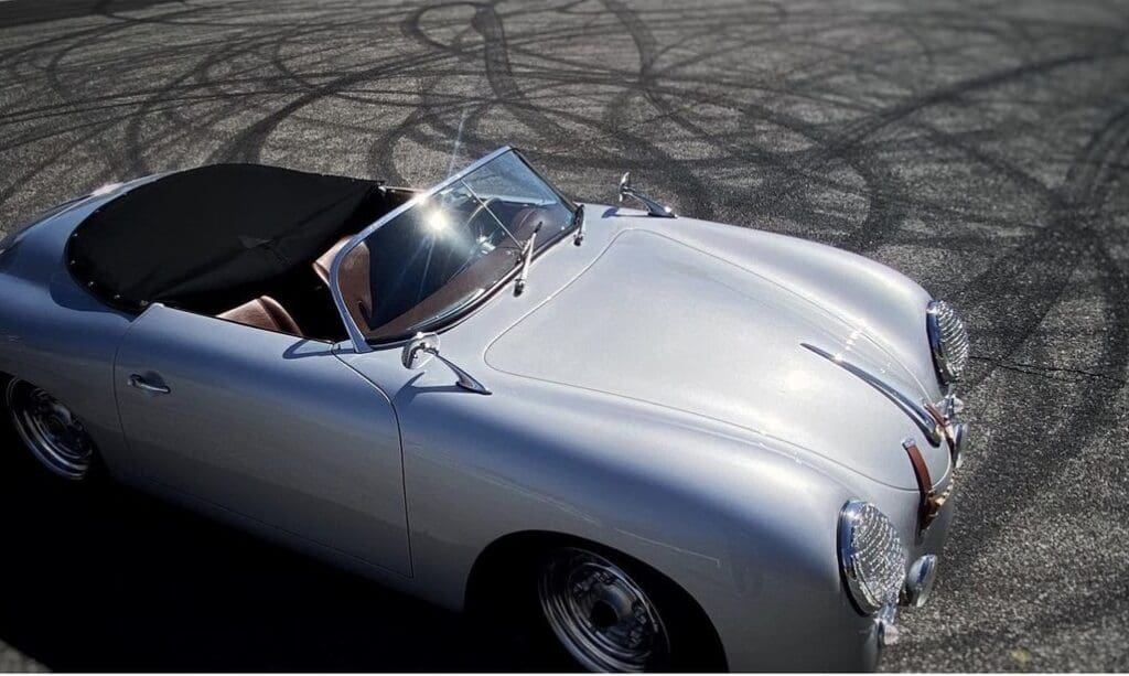 Classic silver convertible sports car parked on asphalt with tire marks.