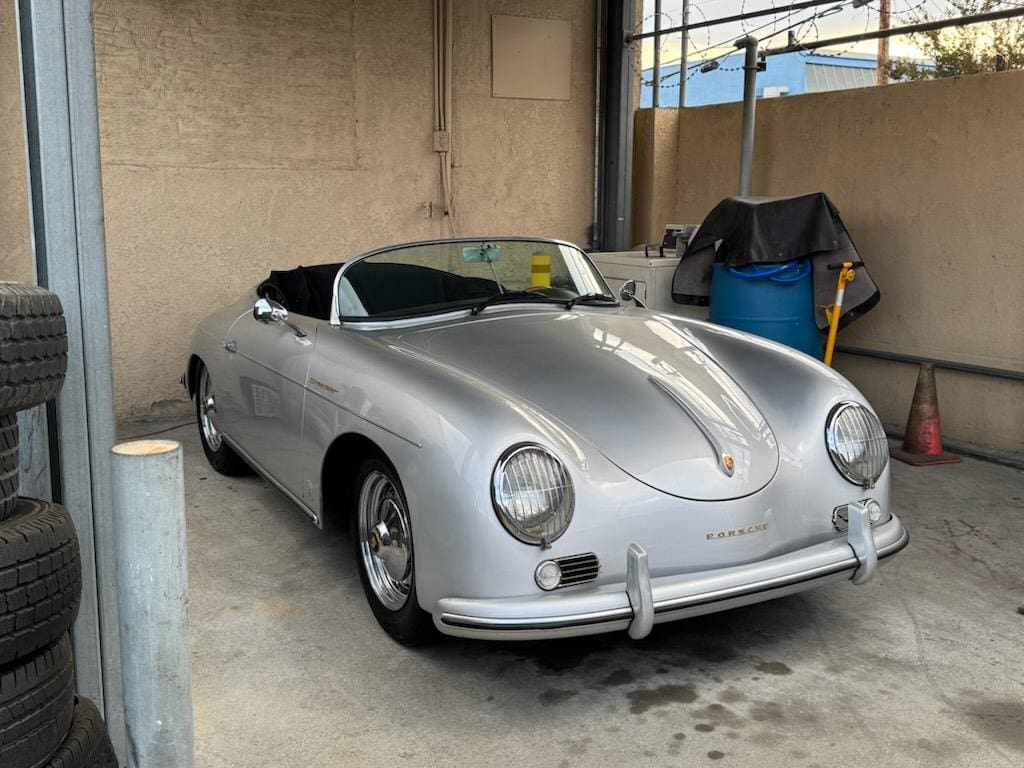 Silver classic convertible car parked inside a garage.