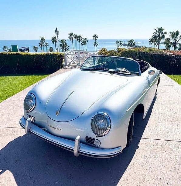 Classic silver convertible parked with ocean view.