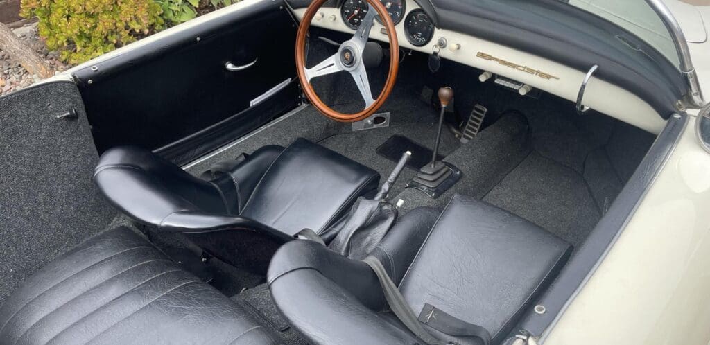Vintage car interior with wooden steering wheel and manual transmission.