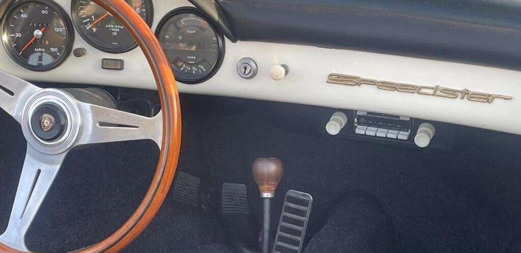 Classic car interior with wooden steering wheel and manual gear shift.