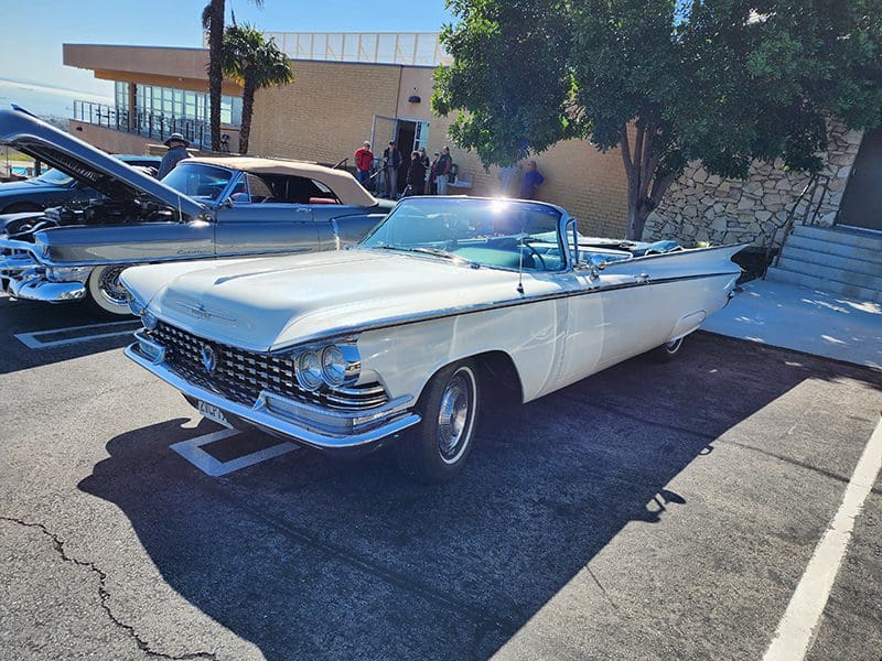 Classic white convertible car parked in a sunny lot.