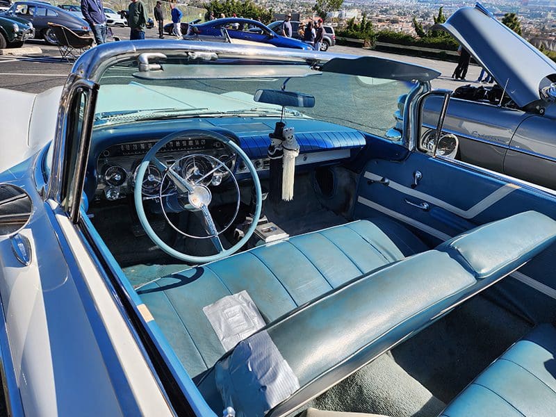 Classic white convertible car parked in a sunny lot.