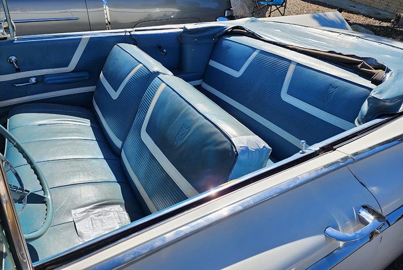 Interior of a vintage blue convertible car with bench seats.