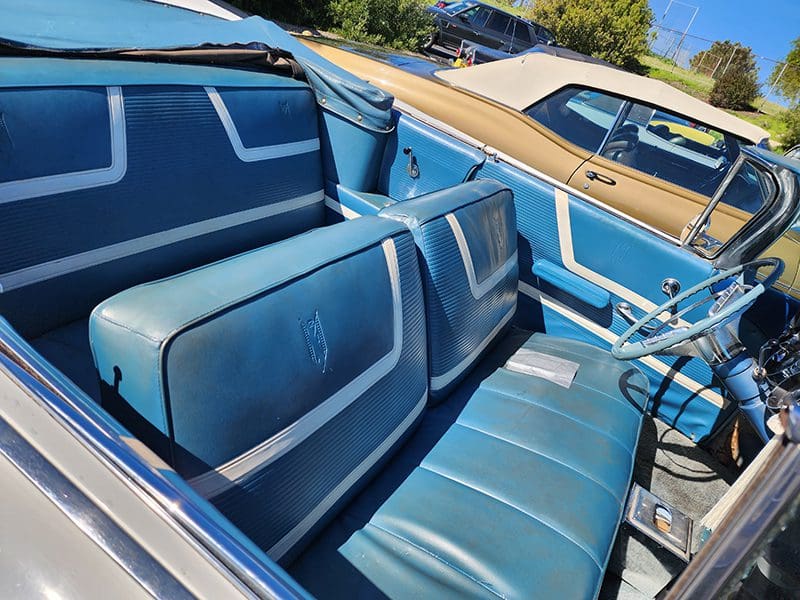Vintage convertible car with blue leather interior seats.
