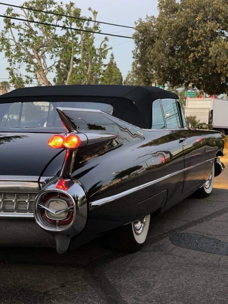 Classic black convertible car with distinctive tail fins and round taillights.