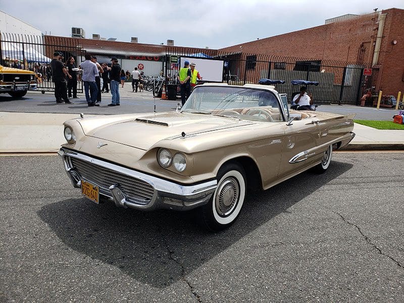 Classic vintage convertible car parked outdoors with people in the background.
