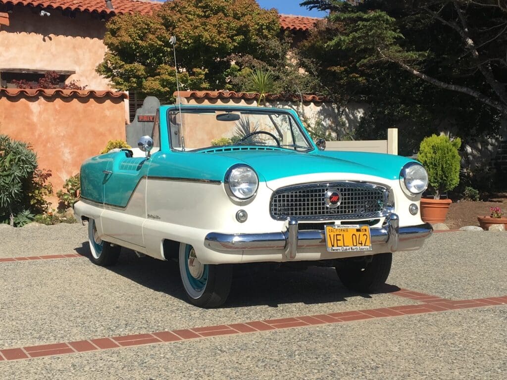 A vintage turquoise and white convertible car parked outdoors.