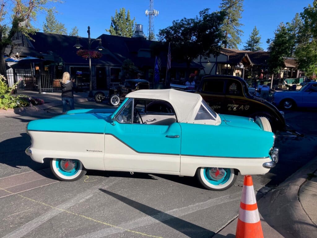 Classic turquoise and white vintage car parked outdoors on a sunny day.