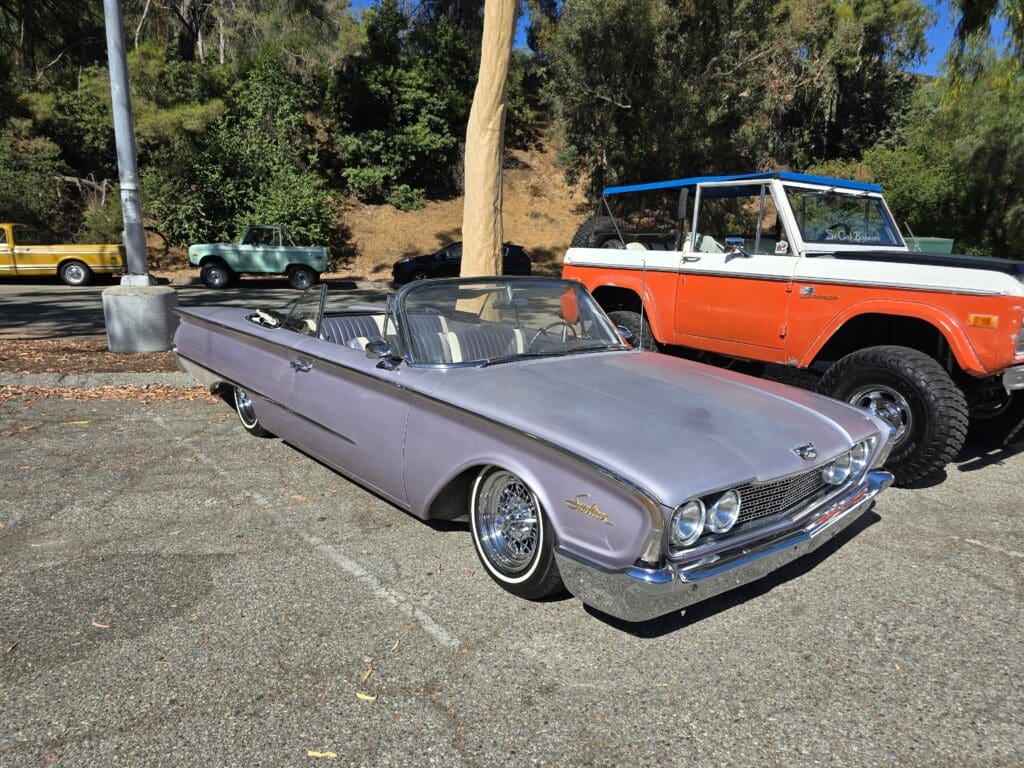 Classic lavender convertible car parked outdoors on a sunny day.