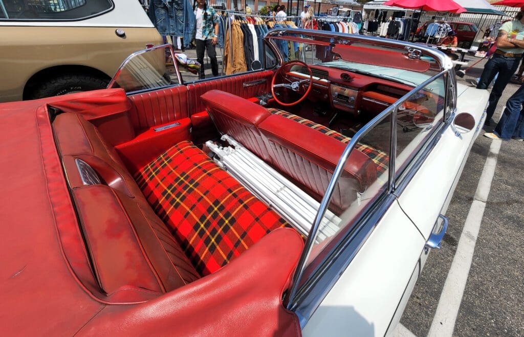 Interior of a vintage car with red leather and plaid seats.
