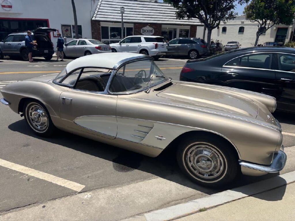 Classic cream-colored vintage car parked in a sunny lot.