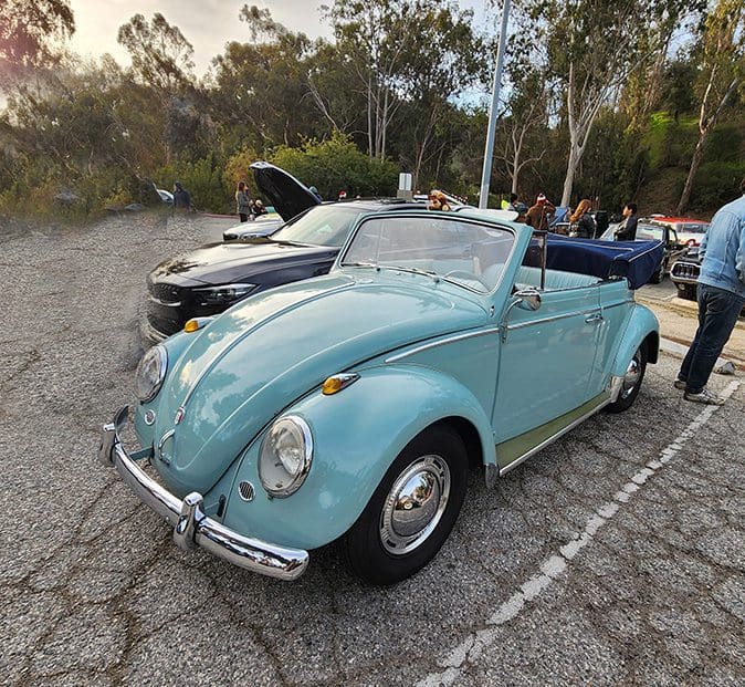 Classic light blue Volkswagen Beetle convertible at a car show.
