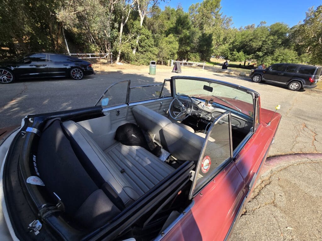 Red classic convertible car with black interior parked outdoors.