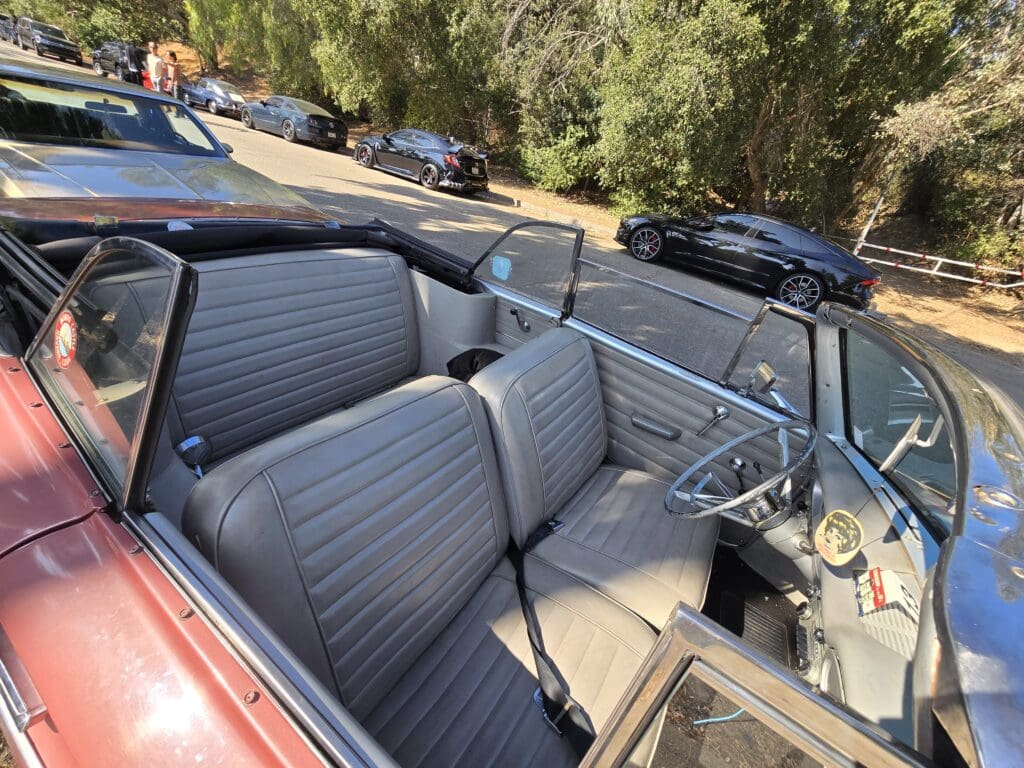 Interior view of a classic convertible car with gray seats and a steering wheel.