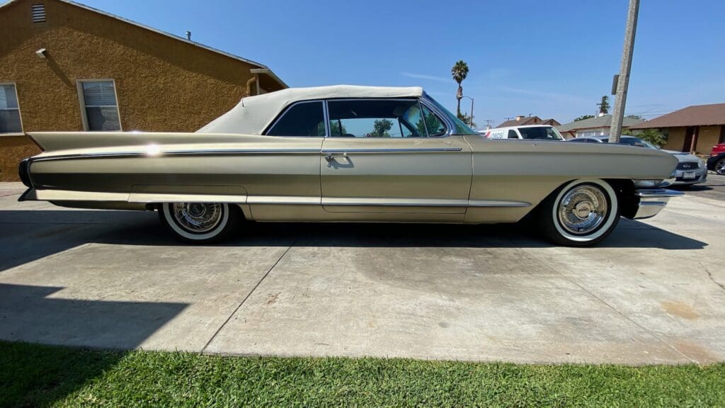 Classic beige vintage car parked on driveway under a clear sky.