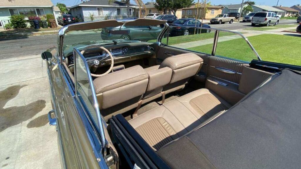 Classic convertible car interior with beige leather seats and a wooden dashboard.