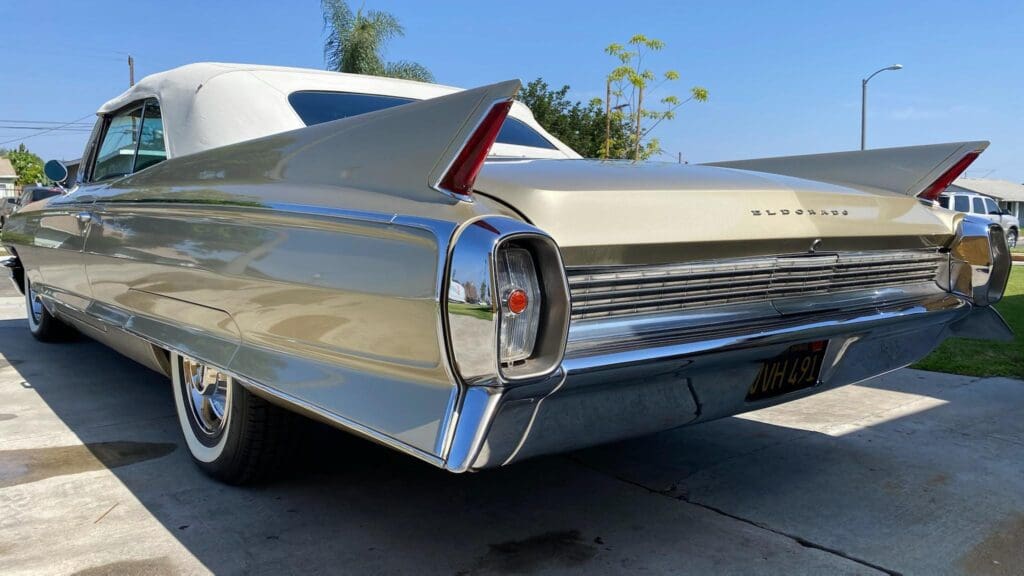 Close-up of a classic car's tail fin and rear light under a sunny sky.