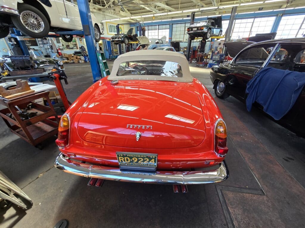 Rear view of a classic red Mercedes-Benz 190SL convertible in a garage.