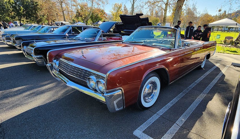 Classic red convertible car with whitewall tires parked outdoors.